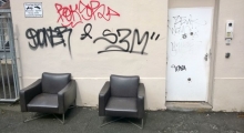 Zwei elegante Ledersessel vor einer Wand mit Graffiti-Tags
