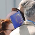 Mann hält kleine EU-Fahne hoch.