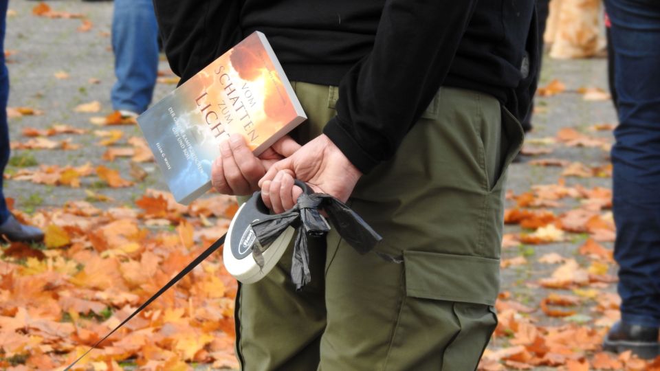 Bild einer Querdenkenversammlung am 19. Oktober in Dortmund. Ein Mensch hält ein Buch mit dem Titel "Vom Schatten zum Licht" in der Hand.