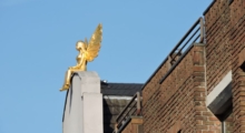 Goldener Engel aus Metal auf einem Hausdach. Lebensgroß.