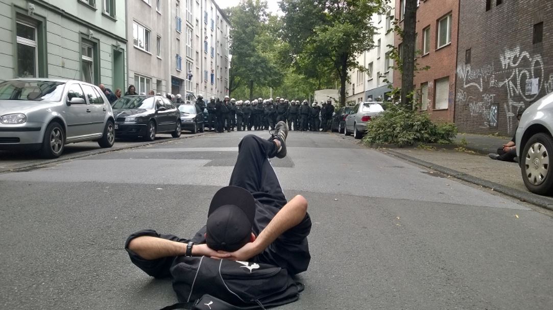 Ein Aktivist liegt ruhig und gelassen auf der Straße vor einer Polizeikette.