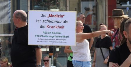 Menschen auf einer Querdenken-Demonstration mit einem Schild auf dem "Die Medizin ist schlimmer als die Krankheit" steht. Aus dem Jahr 2020.